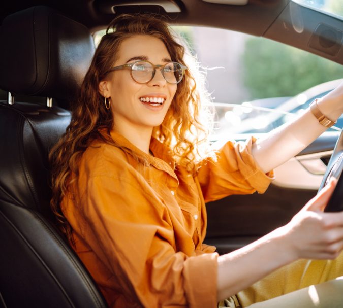 Stylish woman driving a car. The traveler is the driver. Automobile travel. Sharing a car. Lifestyle concept.