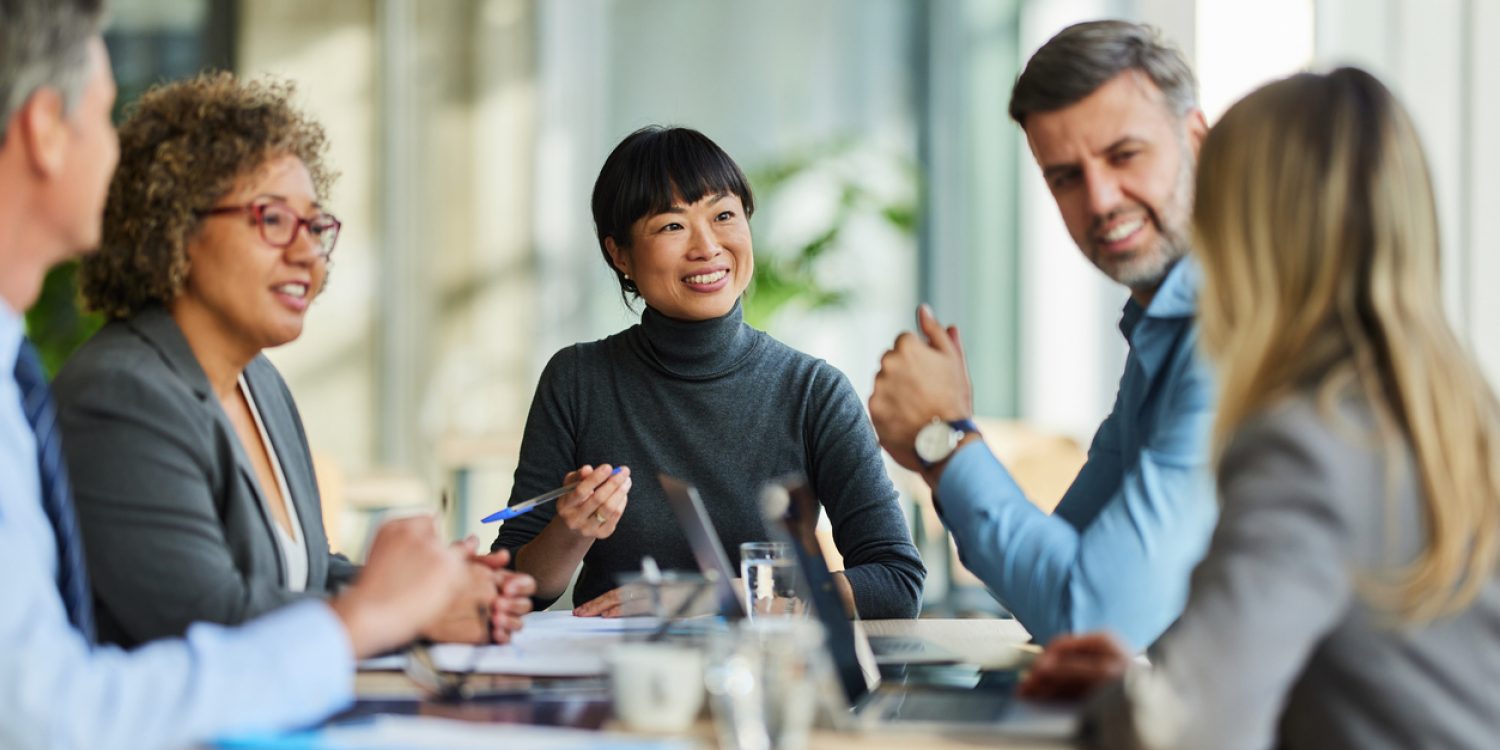 Group of happy multiracial entrepreneurs communicating during a meeting in the office. Focus is on Japanese woman.