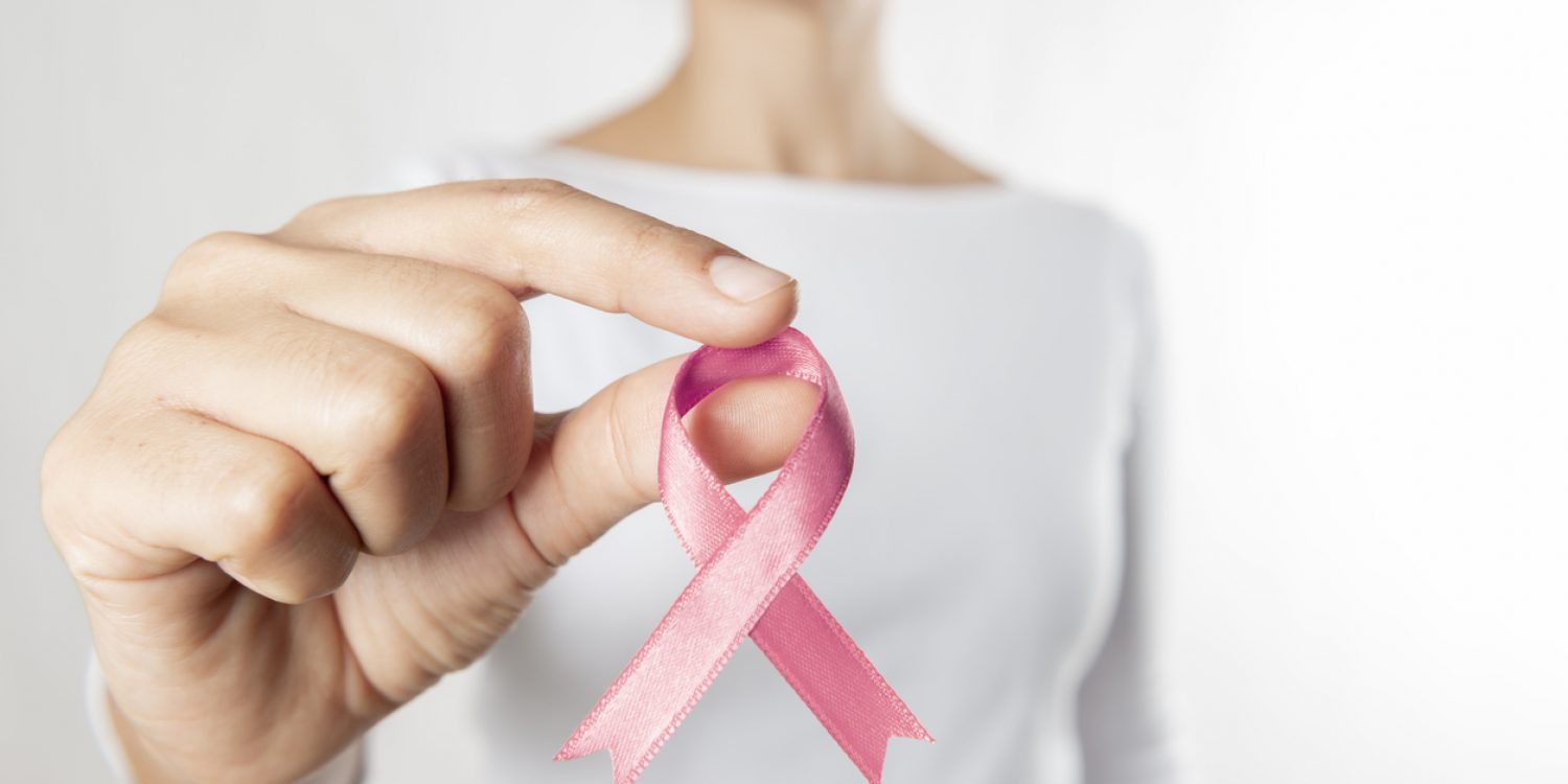 Hands holding pink awareness ribbon.