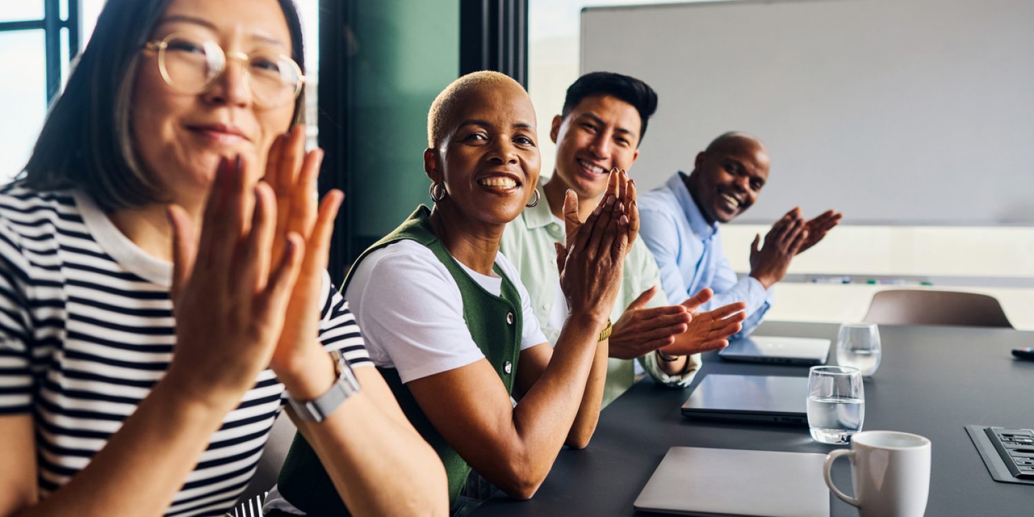 Happy multi-ethnic software engineers clapping after achieving a milestone in coding project