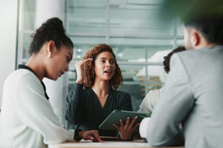 Woman, lawyer and tablet at meeting with team, planning and discussion for review for legal case in office. People, attorney and digital touchscreen with group, negotiation and feedback at law firm