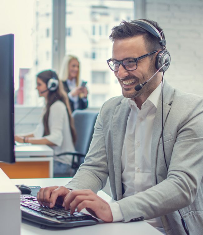 Handsome technical support agent using desktop computer in office.